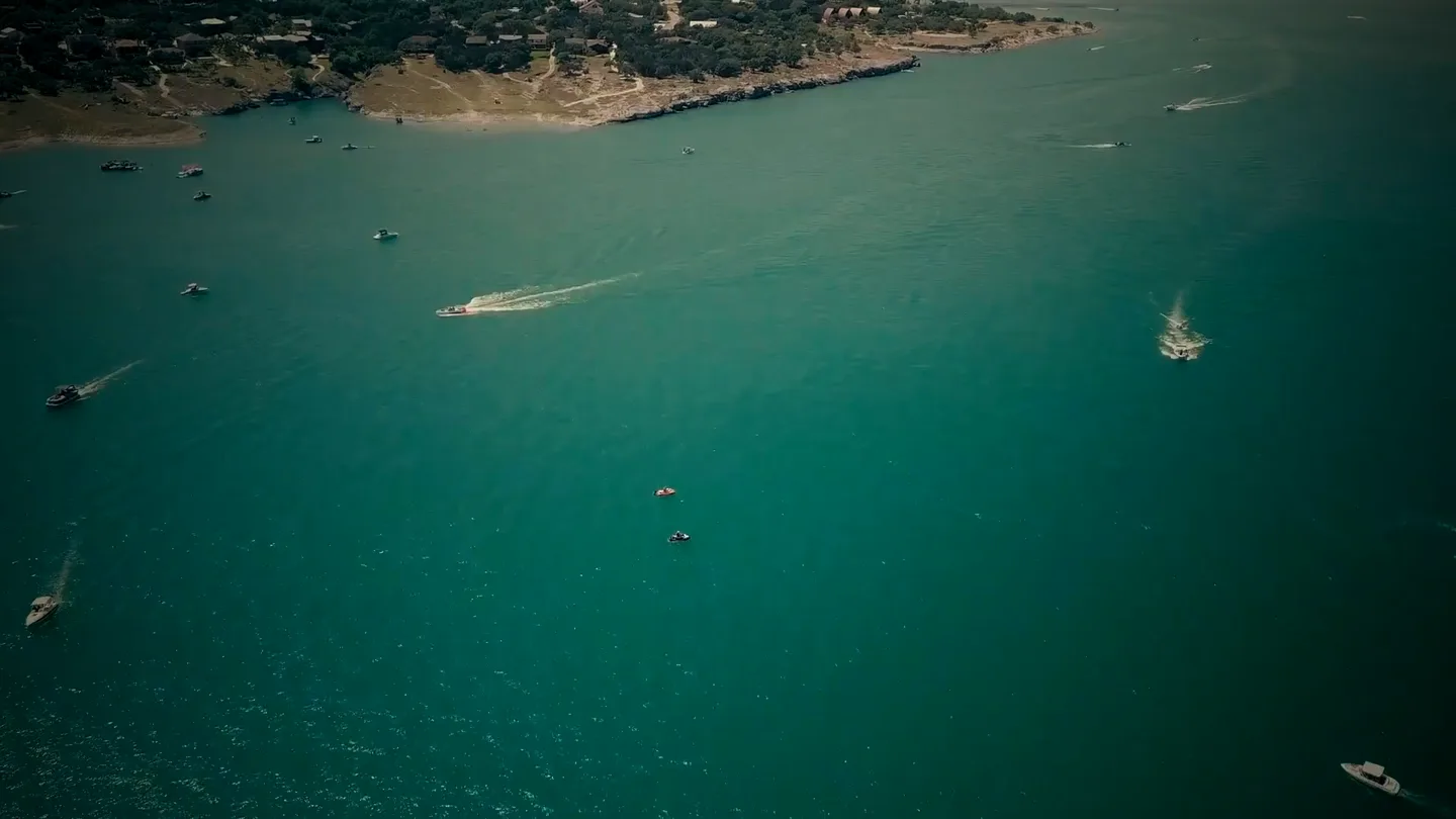Aerial view of Canyon Lake's emerald open water dotted with boats